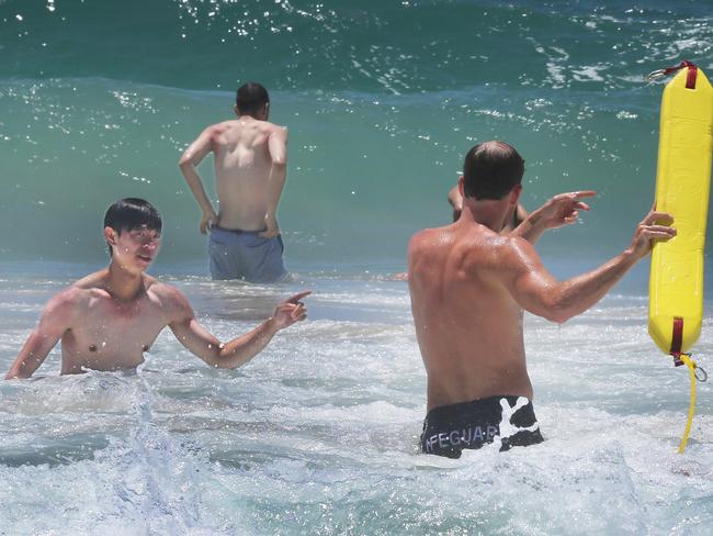 Lifeguards at Surfers Paradise beach keep an eye on beachgoers and keep them swimming between the flags on one of the busiest days of the year. Promotional people on the beach.. Picture Glenn Hampson