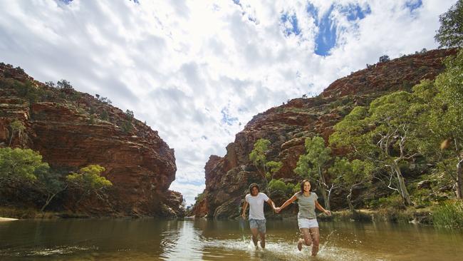 Visitors run through the water at Ellery Creek Big Hole. Tjoritja / West MacDonnell National Park stretches for 161 km west of Alice Springs. Explore and appreciate the scenic beauty and history of the area on foot, swim in a waterhole, or pitch a tent for a longer stay. Picture: TOURISM CENTRAL AUSTRALIA