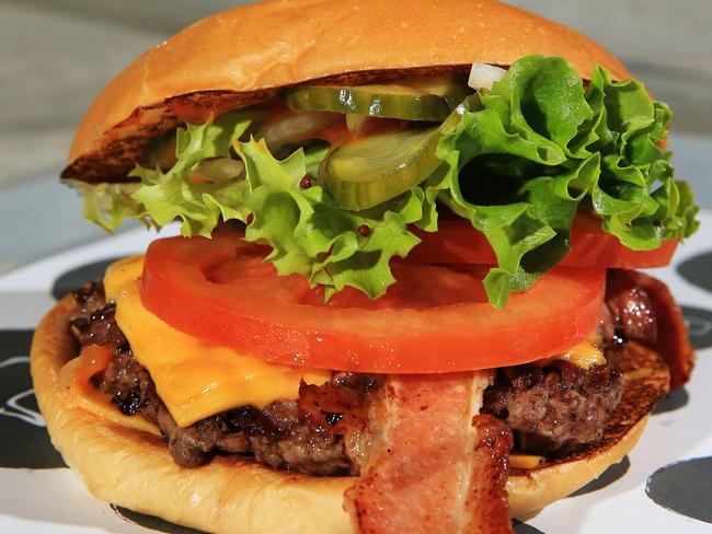Neil Perry pictured with his new range of burgers at Burger Project in World Square. Chef David Chang has caused controversy by saying Australia 'f*@% up burgers' more than anyone else in the world, Perry disagrees. A photo of a Cheese and Bacon burger. Picture: Toby Zerna