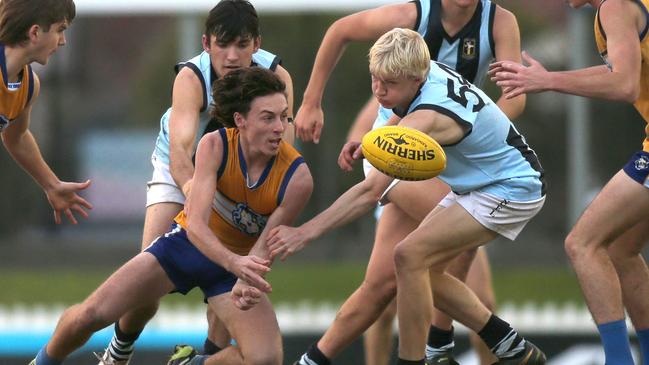 Sacred Heart’s Cruz Polkinghorne gets a handball out of the pack past Immanuel’s Isaiah Wilksch in their clash at Glenelg Oval on Saturday night. Picture: Dean Martin