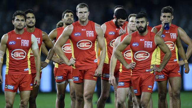 Gold Coast players make their way off Etihad Stadium.