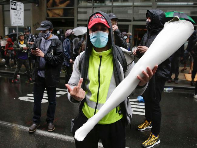 A man makes a rude gesture as he holds a looted mannequin leg during demonstrations. Picture: Jason Redmond