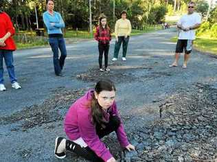 Kristy Goldsby and neighbours check out Avocado Heights potholes. Picture: Bruce Thomas