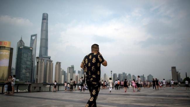 A shows a man wearing an outfit with golden dollar symbols walks down the Bund overlooking the financial district of Pudong in Shanghai. (AFP PHOTO/JOHANNES EISELE)