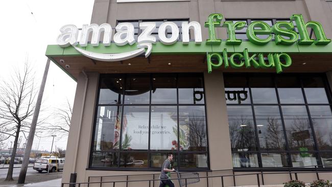 An Amazon worker wheels back a cart after loading a bag of groceries into a customer's car at an AmazonFresh Pickup location Tuesday, March 28, 2017, in Seattle. Amazon began testing the new grocery pick-up service, currently open only to Amazon employees, Tuesday in Seattle. Eventually, members of Amazon's $99-a-year Prime loyalty program will be able to order groceries online and drive to a pick-up location at a scheduled time, where crews will deliver items to the car. Amazon says orders will be ready in as few as 15 minutes after being placed. (AP Photo/Elaine Thompson)