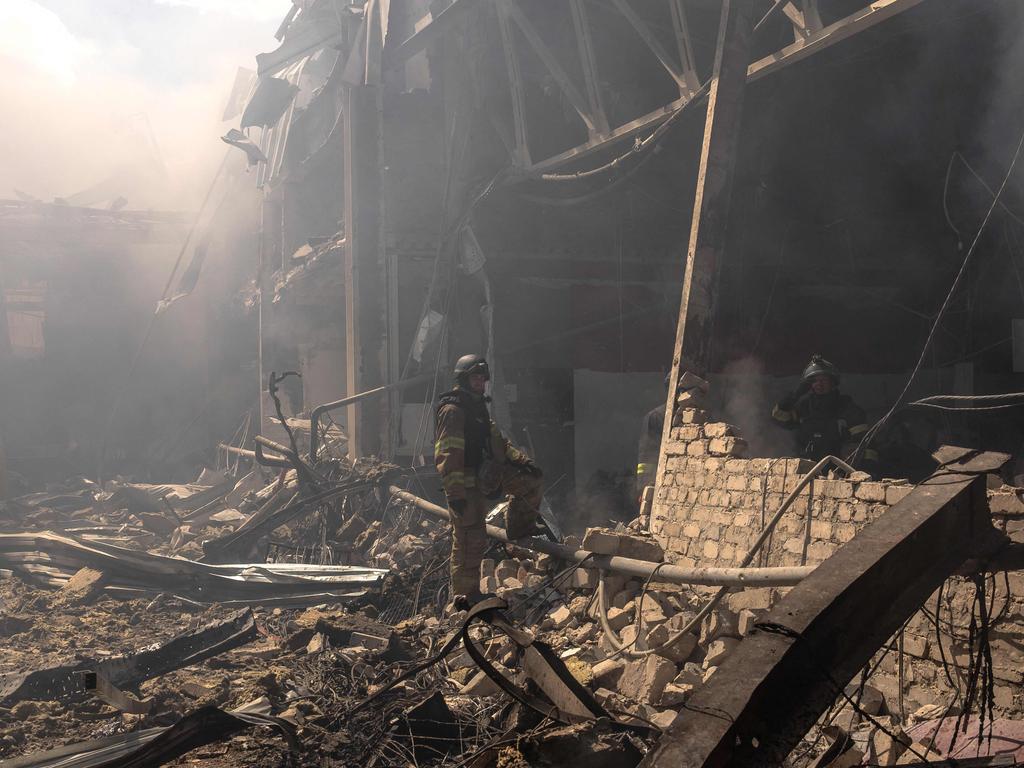 A Ukrainian emergency and rescue personnel stand in the debris as they operate at the site of the destroyed supermarket following a Russian strike. (Photo by Roman PILIPEY / AFP)