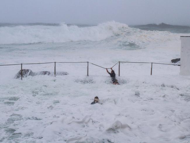 Two teens ignore storm warning and cling on to railing at Bronte Beach, Sydney, Australia. Picture: bill Morris