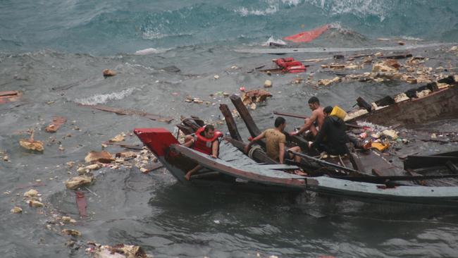 2010: Asylum seekers cling to what remains of their wooden fishing boat after it broke apart when it crashed onto cliffs while trying to land at Christmas Island. 42 survivors were pulled from the water but at least 28 were drowned. Picture: Amy Rossbach