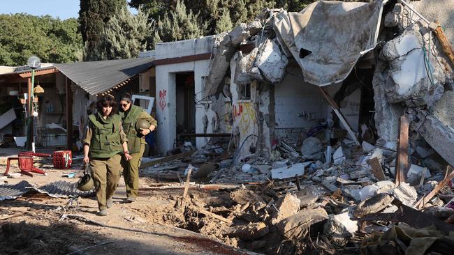 Israeli army soldiers on patrol pass by damaged houses in the kibbutz of Kfar Aza in the country’s south near the Gaza Strip. Picture: AFP