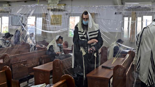 Ultra-Orthodox Jews pray outside in a synagogue divided with plastic sheets in the religious Israeli city of Bnei Brak, near Tel Aviv. Picture: AFP