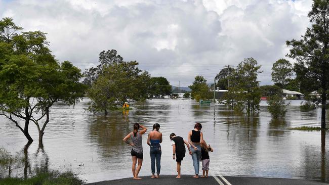 A family stays next to a flooded street in Lawrence on March 1, 2022. Photo: SAEED KHAN / AFP