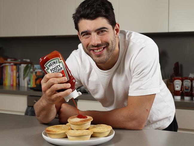 MELBOURNE, AUSTRALIA - August 7, 2023. Footy Food Prices. Melbournes Christian Petracca favourite food at the footy is a meat pie and sauce.    Photo by Michael Klein.