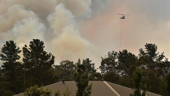 A helicopter prepares to drop water on a large bushfire in Bargo. Picture: AFP