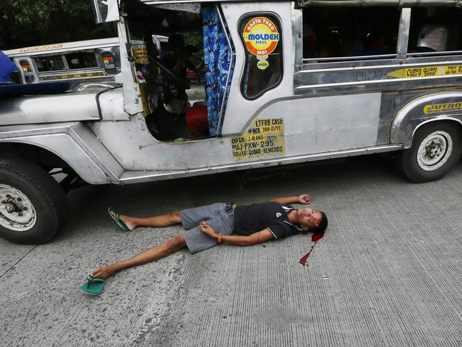 A bloodied protester lies next to a passenger vehicle after he was injured in a violent dispersal outside the US Embassy in Manila. Picture: Bullit Marquez.