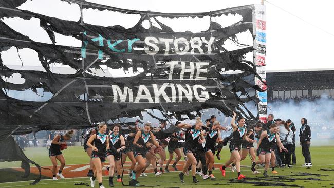 The weather destroys the Port banner as the girls run through. Picture: Sarah Reed/AFL via Getty Images