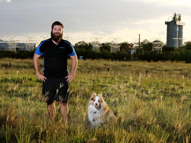 Yatala resident Brendan Ellison with dog Bailey, and the Gold Coast light sign visible in the distance. Picture: David Clark/AAP