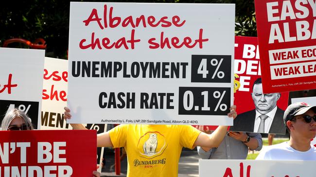 Protesters hold signs in a park behind the house that Albanese visited. Picture: Toby Zerna / News Corp Australia