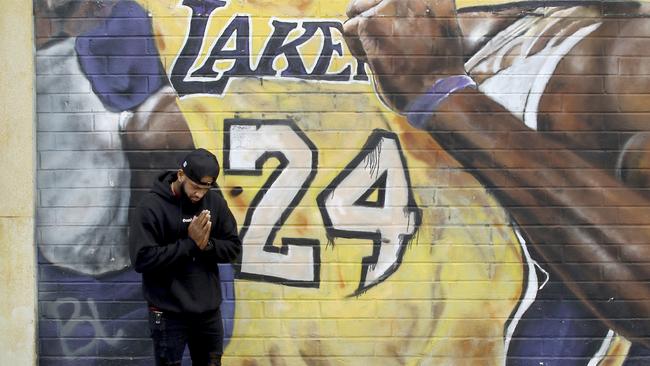 A man pays respects at a mural of Kobe Bryant in an alley in downtown Los Angeles after word of the Lakers star's death in a helicopter crash, Sunday, Jan. 26, 2020. (AP Photo/Matt Hartman)