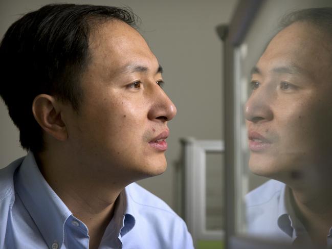 FILE - In this Oct. 10, 2018, file photo, He Jiankui is reflected in a glass panel as he works at a computer at a laboratory in Shenzhen in southern China's Guangdong province. A Chinese investigation says Chinese scientist He, behind the reported birth of two babies whose genes had been edited in hopes of making them resistant to the AIDS virus, acted on his own and will be punished for any violations of the law. (AP Photo/Mark Schiefelbein, File)