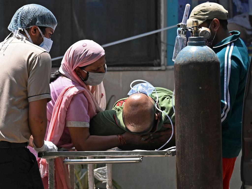 Medical staff and relatives help a coronavirus patient to get in a car at a hospital in New Delhi. Picture: AFP