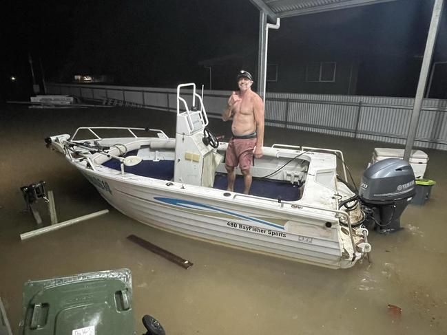 Cardwell resident Brent Churton launches a dinghy from his car port before whisking nearby residents to safety before their home flooded.