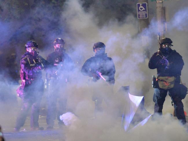 (FILES) In this file photo taken on July 26, 2020 Security personnel stand in a cloud of tear gas in Portland, Oregon early July 26, 2020, as protests continue across the United States following the death in Minneapolis of unarmed African-American George Floyd. - Federal forces deployed in the US city of Portland, rocked by weeks of clashes between demonstrators and law enforcement, will start pulling out of the city on July 30, 2020, the state governor announced. "After my discussions with (Vice President Mike) Pence and others, the federal government has agreed to withdraw federal officers from Portland," Oregon governor Kate Brown tweeted on July 29, 2020. (Photo by Ankur Dholakia / AFP)