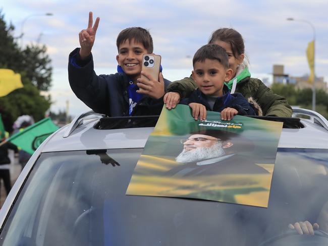 Children carry a picture of slain Hezbollah leader Hassan Nasrallah as displaced residents return to their villages after a ceasefire between Israel and Hezbollah. Picture: AP