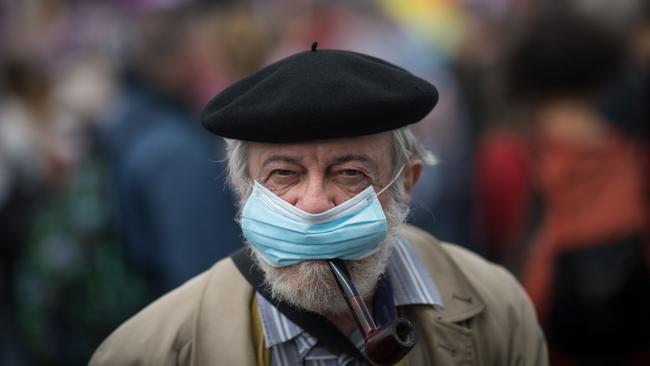 A man smokes a pipe while wearing a face mask. Picture: AFP