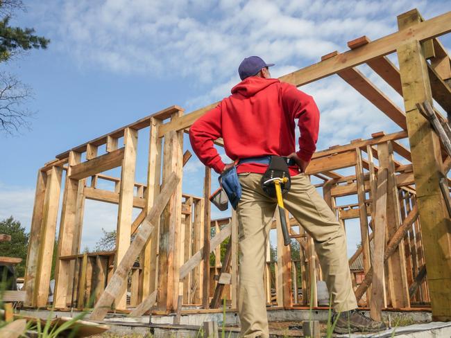 Developing Queensland - roofer, carpenter working on roof structure at construction site.