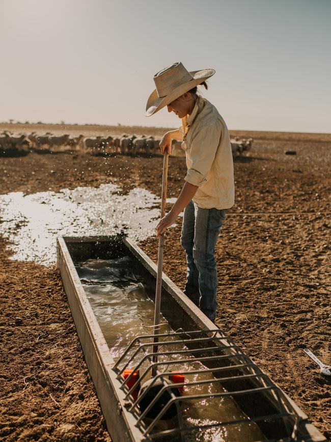 Meg Clothier cleans a trough. Picture: Maddie Brown Photography