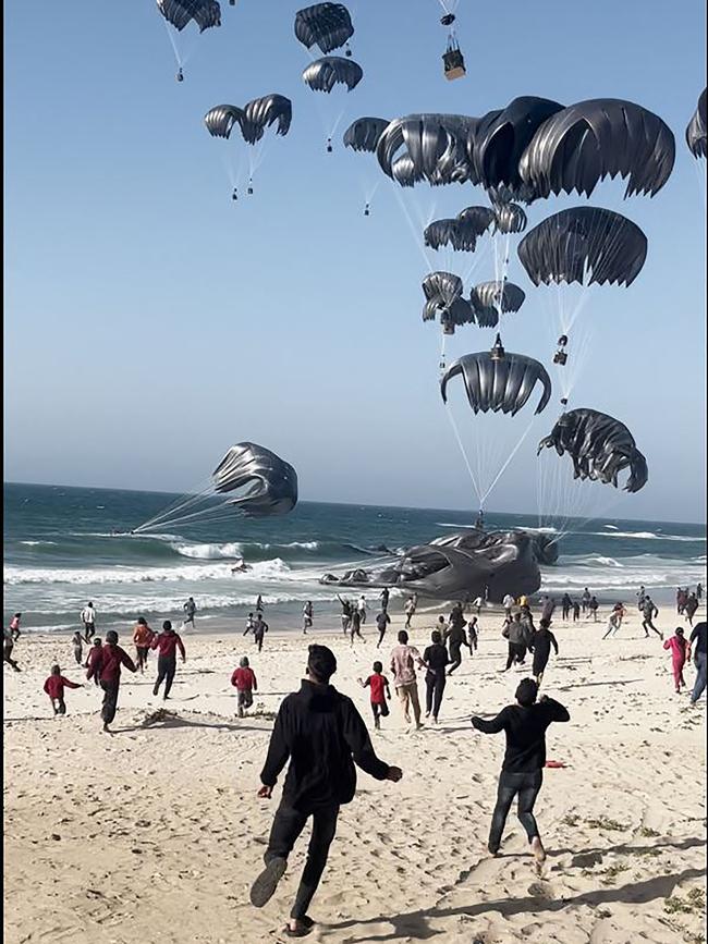 Palestinians run toward food parcels air-dropped from US aircrafts on a beach in the Gaza Strip on Saturday. Picture: AFP