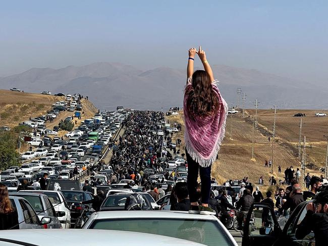 This UGC image posted on Twitter reportedly on October 26, 2022 shows an unveiled woman standing on top of a vehicle as thousands make their way towards Aichi cemetery in Saqez, Mahsa Amini's home town.