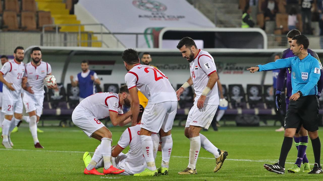 Syria's forward Omar Al-Soma (sitting) is congratulated by teammates after scoring a goal