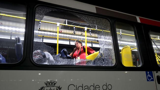 A member of the media stands near a shattered window on a bus.