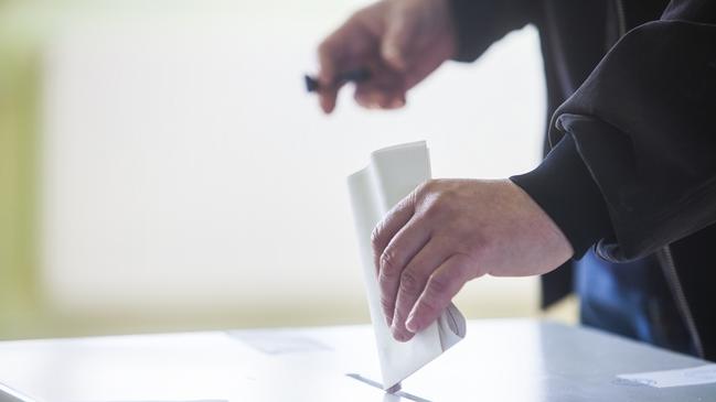 Hand of a person casting a ballot at a polling station during voting. election voting vote polling poll generic Townsville