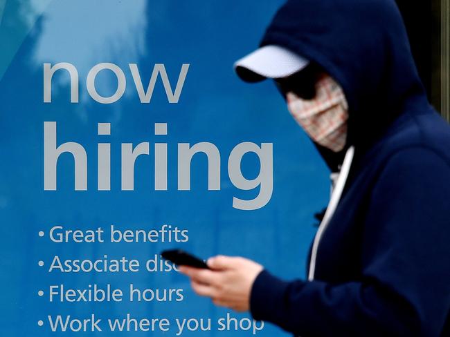 (FILES) In this file photo a man wearing a face mask walks past a sign "Now Hiring" in front of a store amid the coronavirus pandemic on May 14, 2020 in Arlington, Virginia. - Industries hit hard by the coronavirus pandemic showed signs of life in June, hiring 2.4 million workers, payroll services firm ADP said July 1, 2020. With three million hires in May, that means more than five million people are back at work of the 20 million who lost their jobs in March and April. A significant portion of the hirings were accounted for by small businesses of less than 50 workers, which added 937,000 jobs in the month, the data showed, while 961,000 were in leisure and hospitality -- a sector almost entirely shut down by the efforts to contain COVID-19. (Photo by Olivier DOULIERY / AFP)