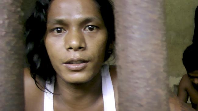 Kyaw Naing, a slave from Myanmar, looks through the bars of a cell at the compound of a fishing company in Benjina, Indonesia.