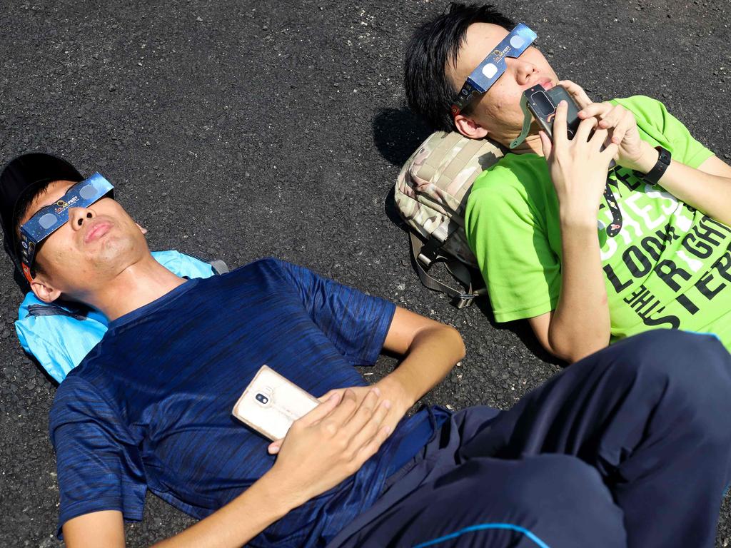 Onlookers all wore solar filter glasses to watch the rare event. Picture: AFP