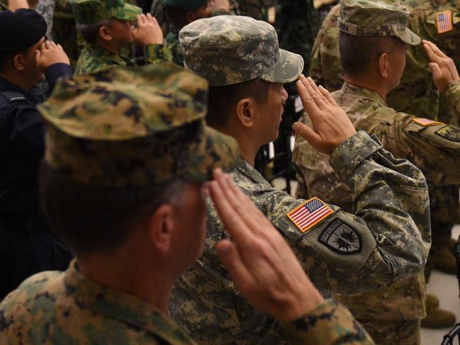 Philippine and US soldiers, along with visiting military attache members, salute as the national anthems of both the US and Philippines are played during the opening ceremony of the annual joint 11-day Balikatan (Shoulder-to-Shoulder) military exercise in Manila on April 4, 2016. US and Philippine troops began major exercises on April 4 as China's state media warned "outsiders" against interfering in tense South China Sea territorial disputes. / AFP PHOTO / TED ALJIBE