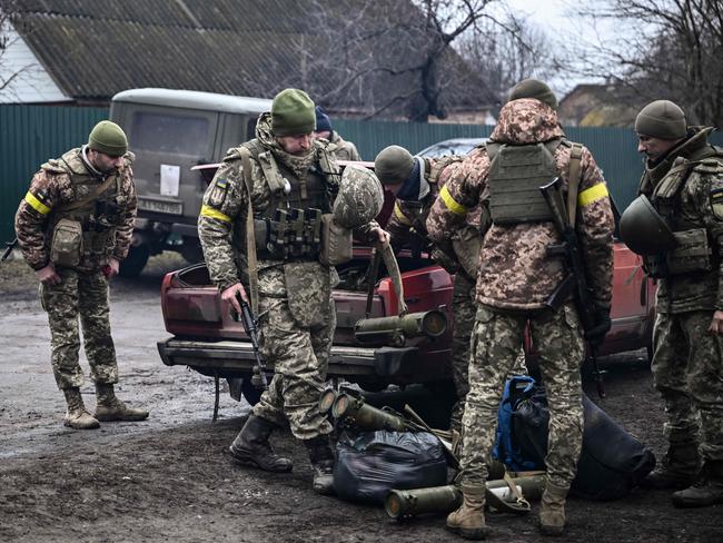 Ukrainian soldiers unload weapons from the trunk of an old car, northeast of Kyiv. Picture: AFP