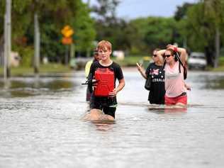 Eleven year-old Jayden Hammond-Sires wades through floodwater with his family in the suburb of Hermit Park in Townsville, Wednesday, February 6, 2019. Residents have begun cleaning up after days of torrential rain and unprecedented water releases from the city's swollen dam, sending torrents of water down the Ross River and into the city, swamping roads, yards and homes. Picture: DAN PELED