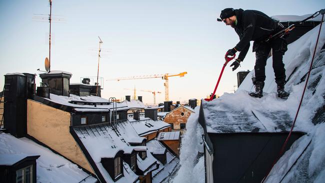 Rooftop snow clearer Andrei Plian gets to work in Stockholm last week. Picture: AFP