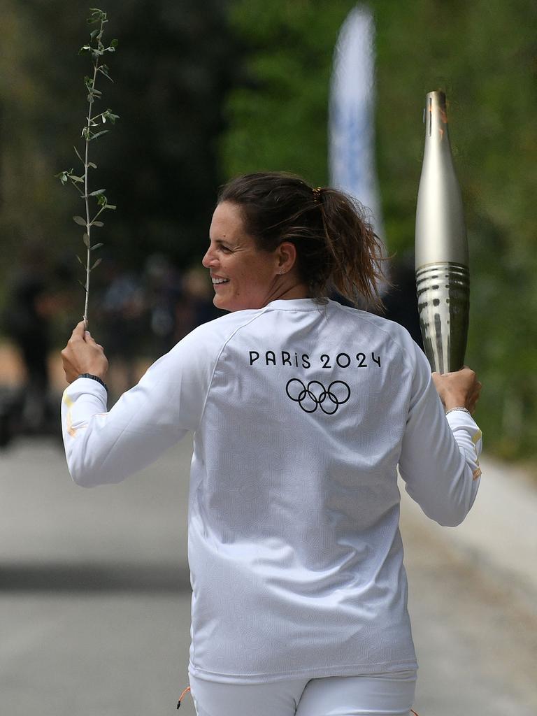 The second torchbearer, French Olympic swimmer Laure Manaudou, runs with the Olympic torch during the lighting ceremony for the Paris 2024 Olympic Games – but the torch will pass through thousands of hands before the opening ceremony on July 26. Picture: Valerie Gache/AFP