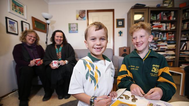 Hugh Bennetts (middle) and Felix Griebe (right) pictured at Georges Hall today banking some money through the school Dolamites program. Picture: Sam Ruttyn