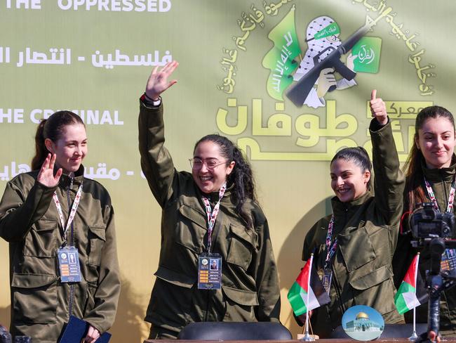 TOPSHOT - Four Israeli hostages wave on a stage before Hamas fighters hand them over to a team from the Red Cross in Gaza City on January 25, 2025. Hamas militants handed over four Israeli women hostages to the Red Cross in a January 25 swap after parading them on a stage at a square in Gaza, an AFP journalist reported. (Photo by Omar AL-QATTAA / AFP)