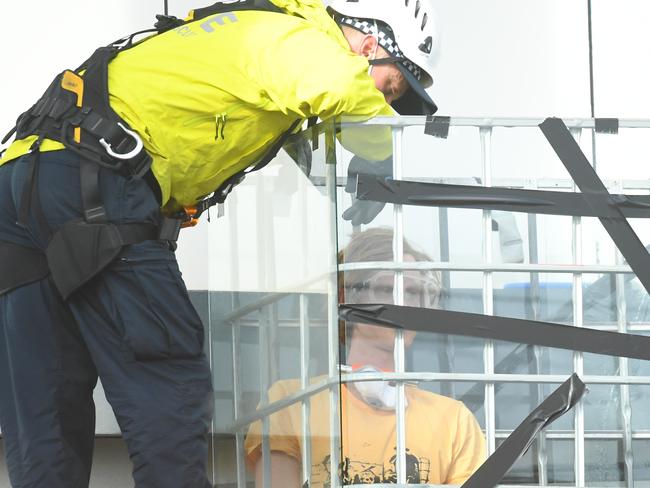 Victorian Police officers work to free a refugee rights activist who is locked to a cage on top of the Chill Restaurant and Bar rooftop next to the Mantra Hotel in Melbourne, Wednesday, June 24, 2020. Protesters are demanding the release of refugees being detained at the Mantra Hotel in Preston. (AAP Image/James Ross) NO ARCHIVING