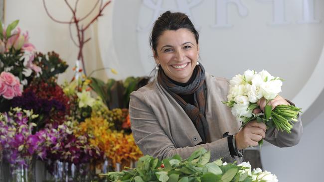 Flower 152 owner and florist Connie Rhigas with a bouquet of white flowers, Classical New York White, perfect for a Mother's Day gift.