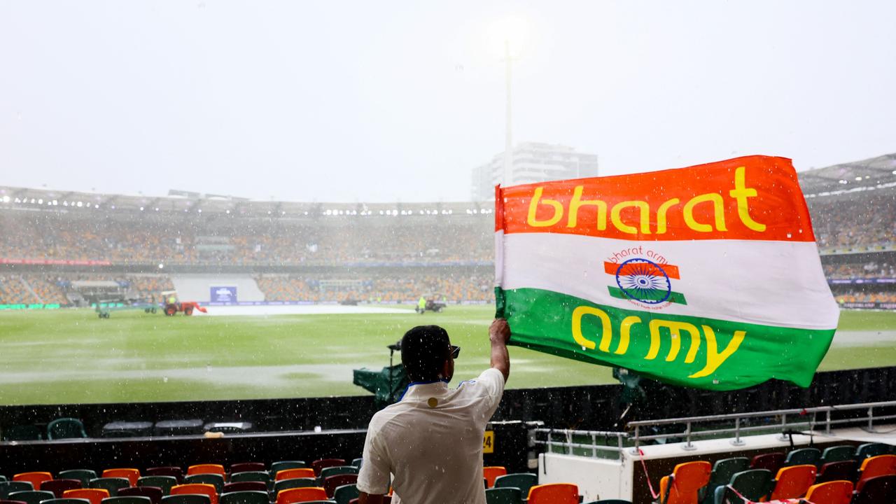 An Indian fan waves a flag from the stands as rain delays play at The Gabba. (Photo by Patrick Hamilton/AFP)