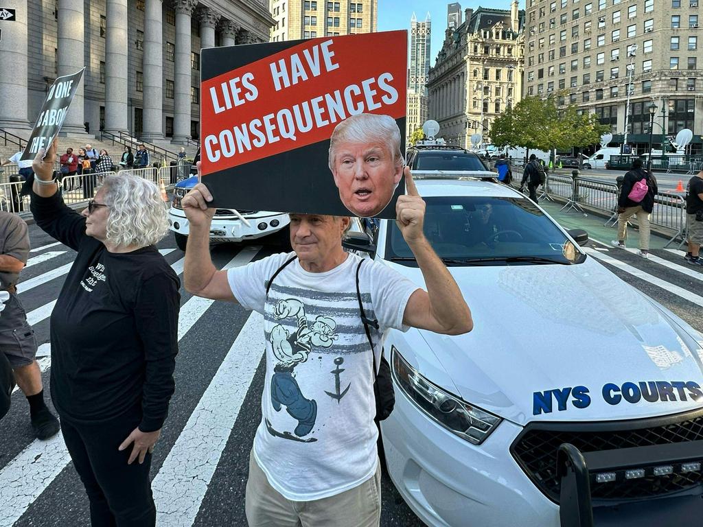 Protesters hold placards before the arrival of former President Donald Trump to New York State Supreme court for the start of the civil fraud trial against him. Picture: AFP