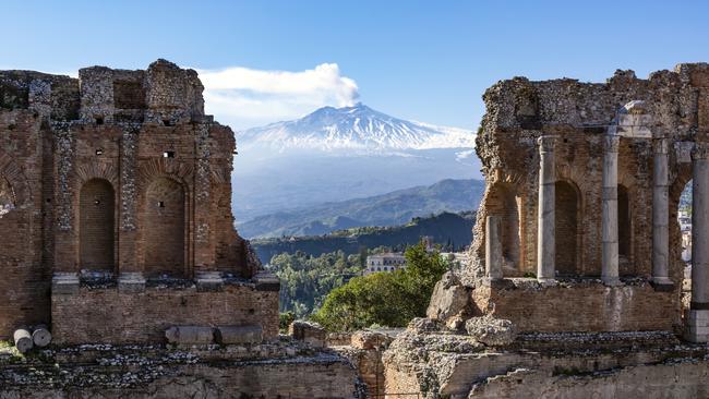 Volcano Etna in Sicily seen through ruins of ancient amphitheatre in Taormina.